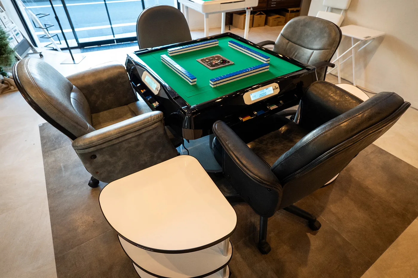 An ALBAN automatic Riichi table seen from above in the showroom, tiles dealt and four chairs around it